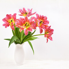 Bouquet of tulip flowers in a white vase on white background