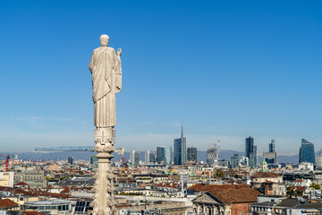Statue on the top of a spire of Milan Cathedral looking down the city center and skyline, Italy