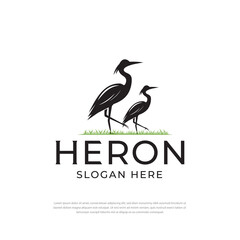 Logo of two storks or flamingos or storks standing tall on green grass.