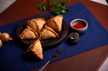 Homemade cakes on wooden utensils with sauce and herbs.