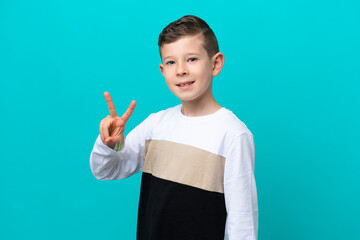 Little kid boy isolated on blue background smiling and showing victory sign