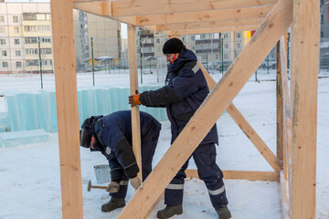 Worker in winter overalls with a hammer in his hand