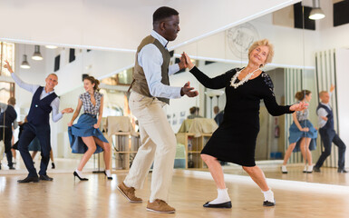 Woman pensioner with african man practising charleston