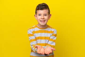 Little caucasian boy isolated on yellow background holding copyspace imaginary on the palm to...