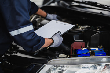 Professional mechanic working on the engine of the car in the garage. Car repair service.