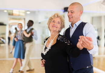 Man and senior woman dancing waltz in studio