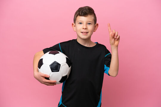Little caucasian football player boy isolated on pink background pointing up a great idea