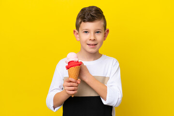 Little caucasian boy with a cornet ice cream isolated on yellow background celebrating a victory