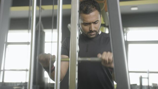bodybuilder doing biceps workout at gym using lat pull machine - concept of fitness, muscle building exercise and determination.