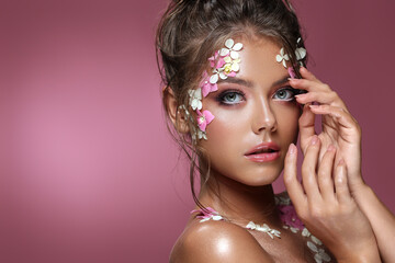 Beautiful caucasian woman with flowers on pink background.