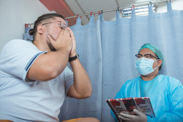 A male patient of mixed asian race gets emotional after feeling relief from a good diagnosis from...