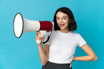 Teenager Ukrainian girl isolated on white background holding a megaphone and smiling