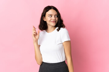 Teenager Ukrainian girl isolated on pink background with fingers crossing and wishing the best