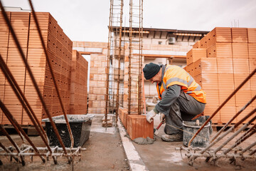Close up of industrial bricklayer installing bricks on construction site. Construction mason...