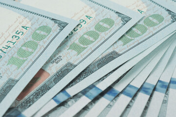 American banknotes of one hundred dollars. Fragment of notes close-up. Focus on digit 100. Economy money savings and US dollar. Light pale background with reduced saturation. Macro