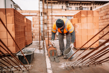 Industrial worker using trowel and tools for building exterior walls with bricks and mortar