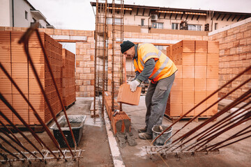 industrial worker, bricklayer and mason working with bricks and building interior walls of house
