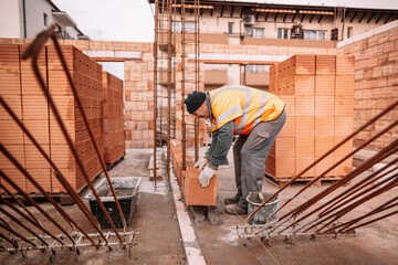 industrial worker, bricklayer and mason working with bricks and building interior walls of house