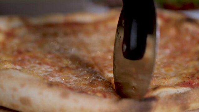 Cooking traditional Italian pizza in oven. Pizza with crispy crust and melted cheese. chef of restaurant cut with roller knife freshly prepared. pizza to serve on  table.
