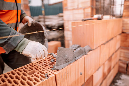 Close up details of industrial bricklayer installing bricks on industrial building, construction site