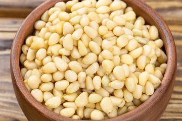 A bowl with pine nuts on a wooden background, delicious, natural. Soft focus.