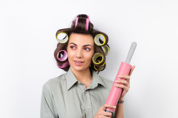 Beautiful housewife. Young cheerful woman with hair curlers, bright make-up, a rolling pin and a whisk in her hands, on a white background.