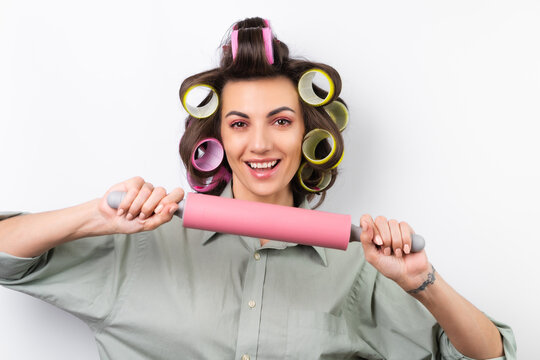 Beautiful housewife. Young cheerful woman with hair curlers, bright make-up, a rolling pin and a whisk in her hands, on a white background.