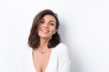 Young woman in a cocktail dress, gold chain and bright spring pink makeup on a white background. Cheerfully smiles.
