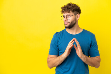 Young handsome caucasian man isolated on yellow background scheming something