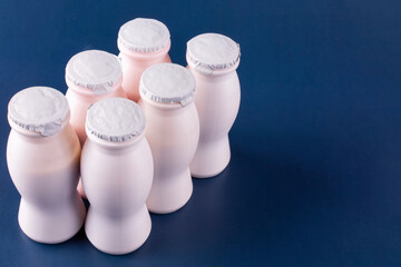 Six bottles of milk yogurt (kefir), lined up in two rows on a blue background. Space for text. The...