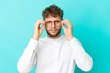 Young handsome caucasian man isolated on blue background With glasses and frustrated expression