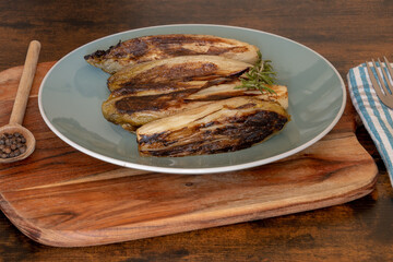 several endives braised in a dish on a wooden base