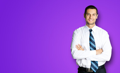 Portrait of happy smiling young brunette businessman in white shirt and blue tie, standing in crossed arms pose, isolated on violet purple background with copy space. Confident business man.