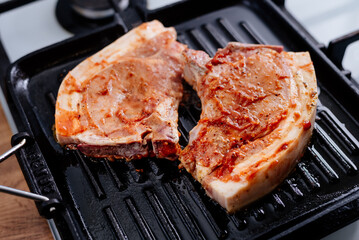 Pork rib steak in sauce and spices fried in a grill pan. The process of cooking pork steak.