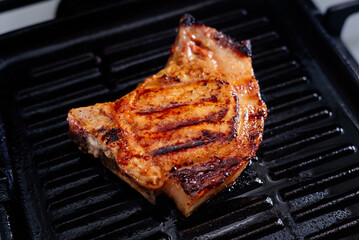 Pork rib steak in sauce and spices fried in a grill pan. The process of cooking pork steak.