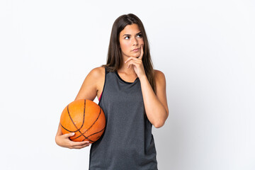 Young brazilian woman playing basketball isolated on white background having doubts while looking up