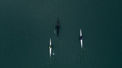 Top view of training of three men on kayaks floating on river water