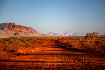 One of the most beautiful red dirt-roads in the Karijini National Park in Western Australia at sunset. - obrazy, fototapety, plakaty