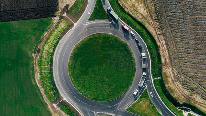 Roundabout traffic of cars and trucks on the circle ring road aerial top view
