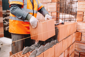 Construction site of new house, worker building the brick wall with trowel, cement and mortar....