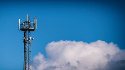 Mobilfunkmast vor blauem Himmel mit Wolke