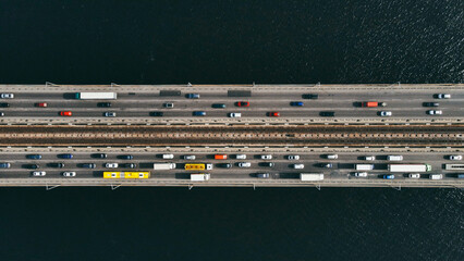 Aerial top view of cars and subway passing the bridge over the river in the city