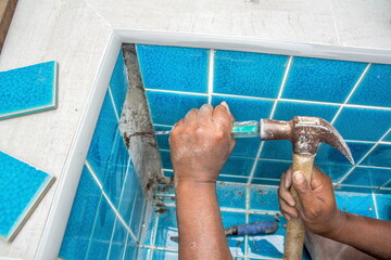 Tiled pool. The man hand while using spacer for installing tiles.	