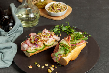 Two bruschettas with microgreens, sprouts and prosciutto. Close-up on a black plate.
