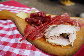 Wooden cutting board full of typical cured meats and porchetta of Ariccia, Castelli Romani, Rome, Lazio, Italy