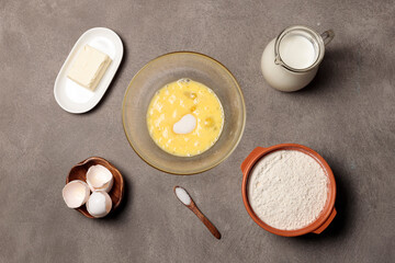 Kneading the dough in a bowl. Beaten eggs with sugar in a bowl and ingredients for making dough.