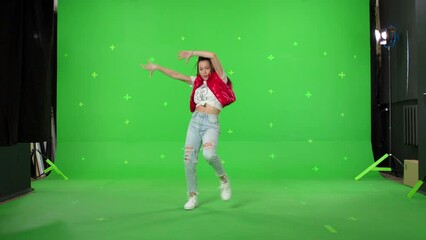 A young woman dancing on a green screen background. Attractive girl making content for social media. Modern blogger creating a master class. Chroma key