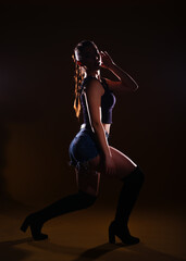 Obraz na płótnie Canvas High-contrast silhouette picture of a sexy female model posing on a dark background