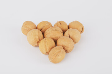 Walnuts are lined with a triangle on a white background in the form of an arrow or billiard balls