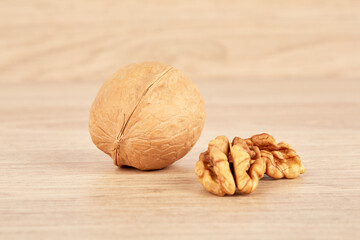 The walnut is whole, and next to it lies a peeled walnut.